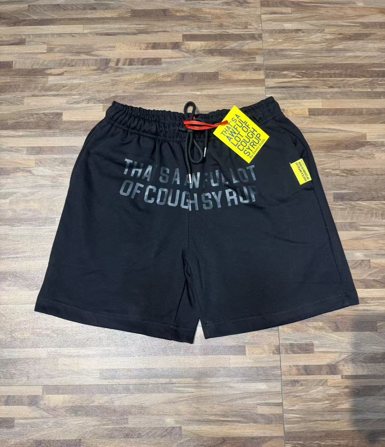 THAT'S A AWFUL LOT OF COUGH SYRUP Black Graphic Shorts — front